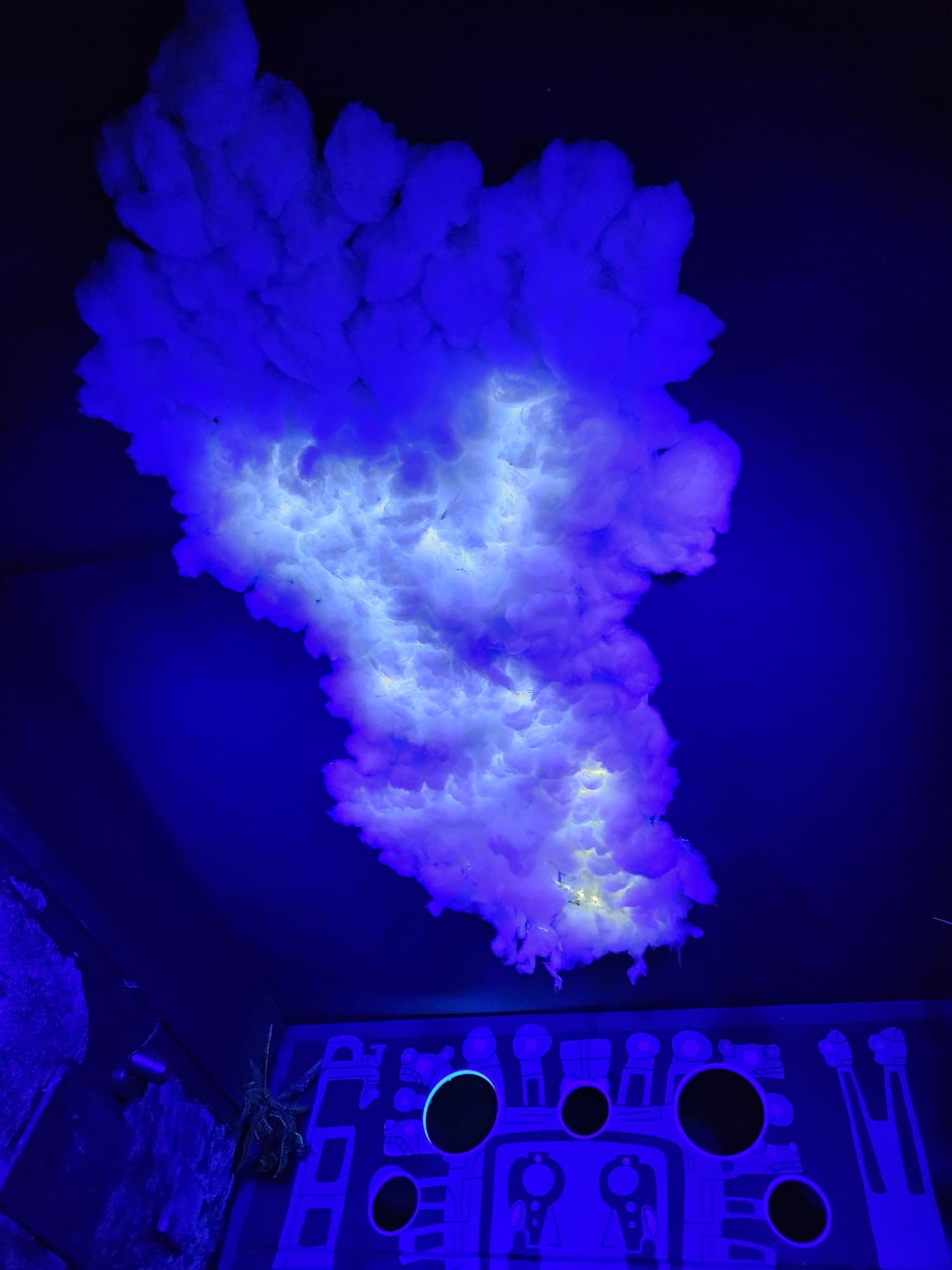 Le nuage suspendu au-dessus du mur de jeu, sous lumière noire
